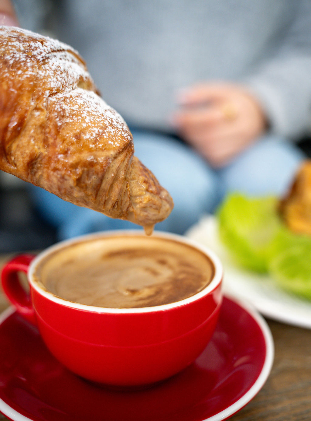 A croissant dipped into a flat white